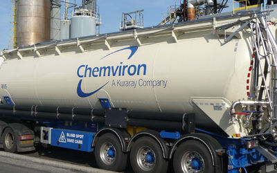A truck with the “Chemviron” logo. In the background is a chemical plant.