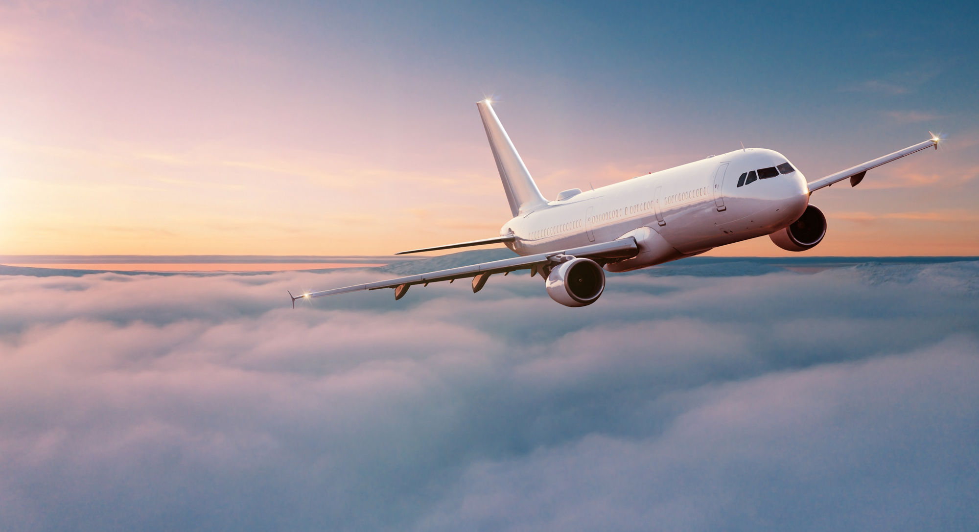 Commercial airplane jetliner flying above dramatic clouds in beautiful sunset light. Travel concept.