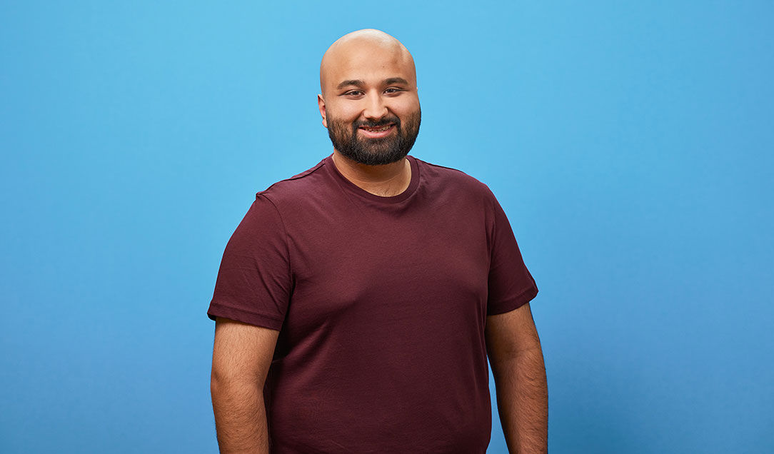 Portrait of a young employee against a blue background.