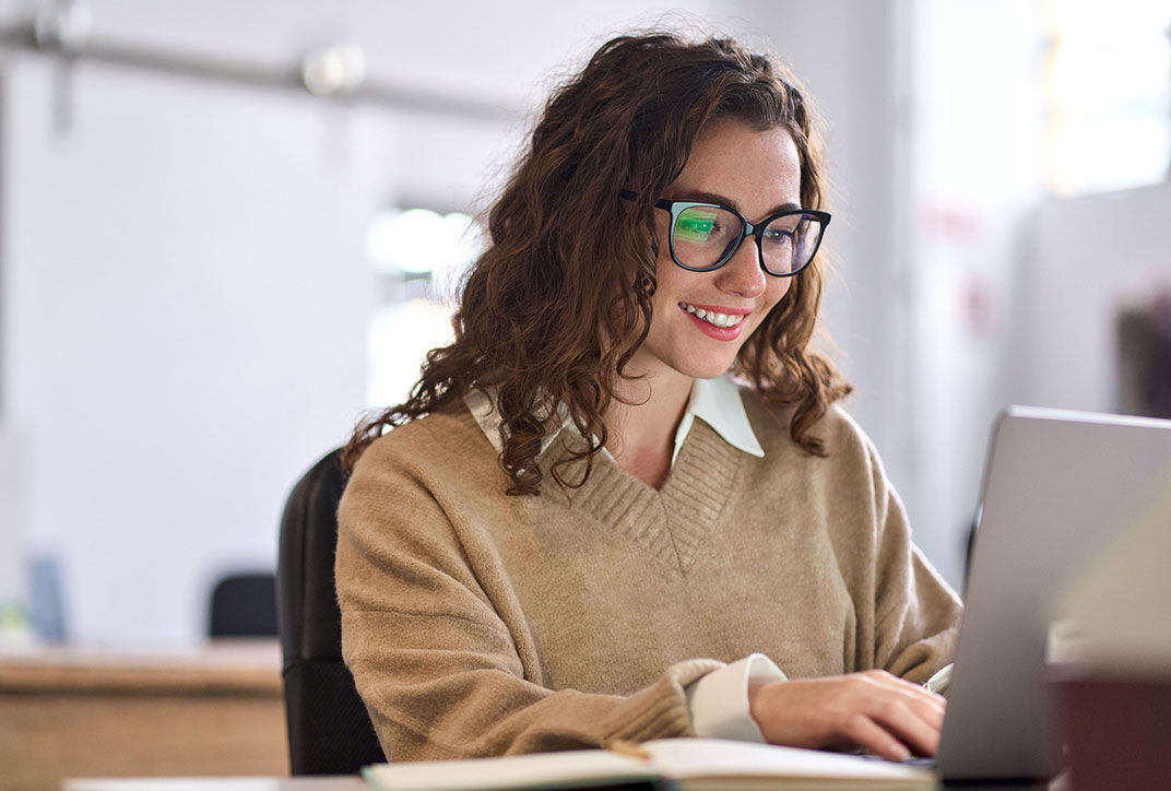 A female employee is working intently on a project on her laptop.