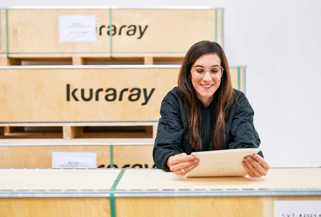 A female employee leans over a wooden box and inspects documents.