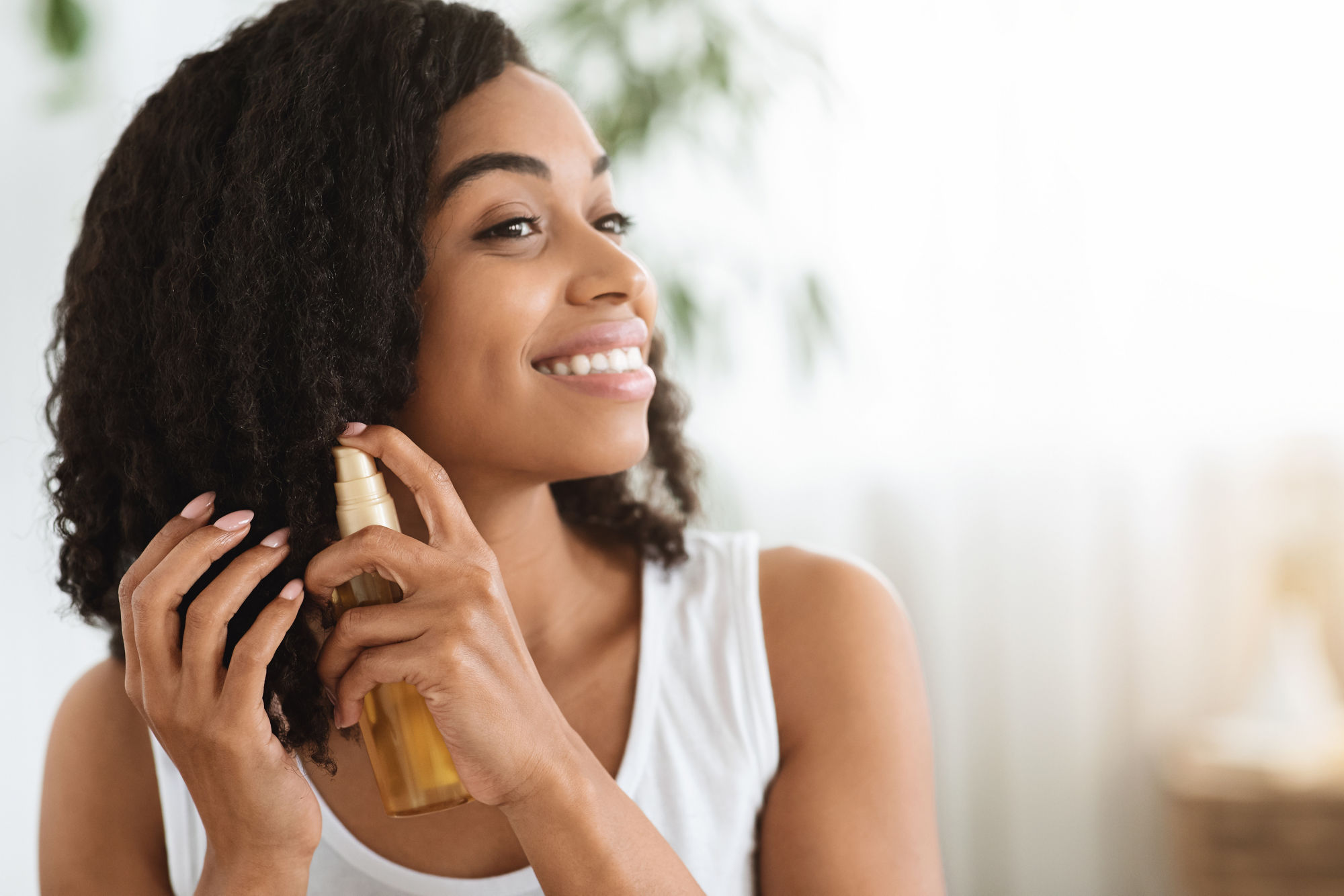 Hair Care. Happy Afro Woman Using Oil For Split Ends While Getting Ready At Home, Closeup Image With Copy Space