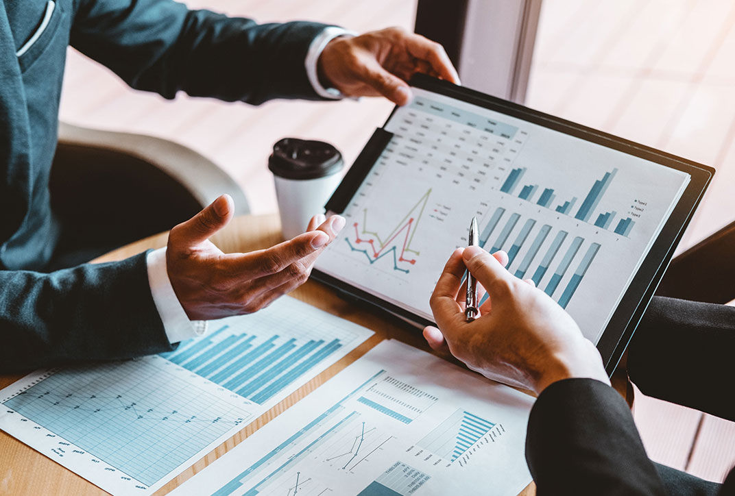 Two people analyze business data on a tablet displaying charts.