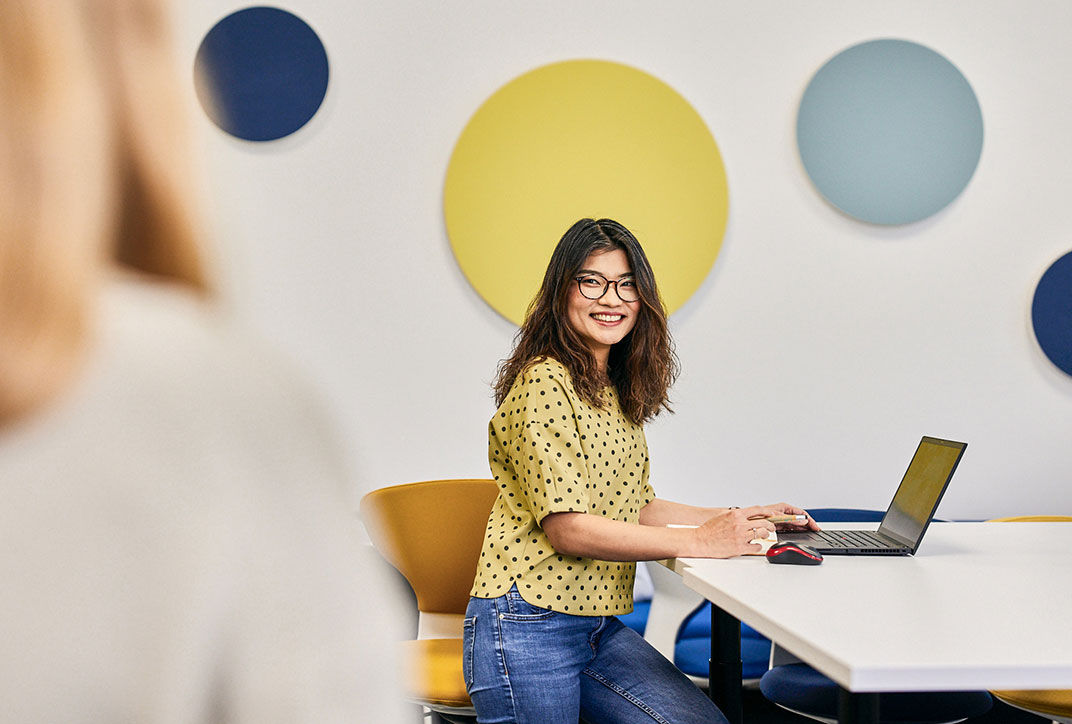 A woman sits with her laptop in a meeting room.