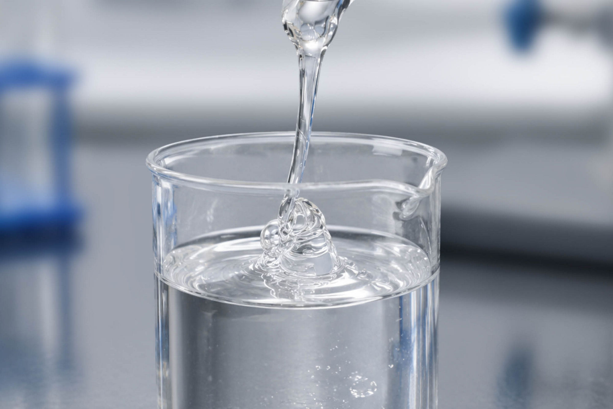 Clear liquid being poured into a glass beaker.