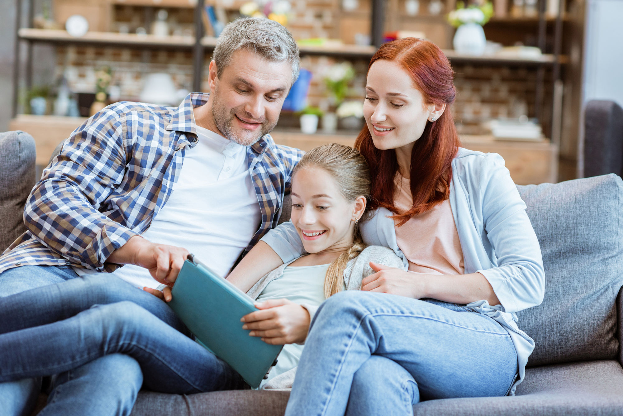 smiling parents and teenage girl using digital tablet together at home