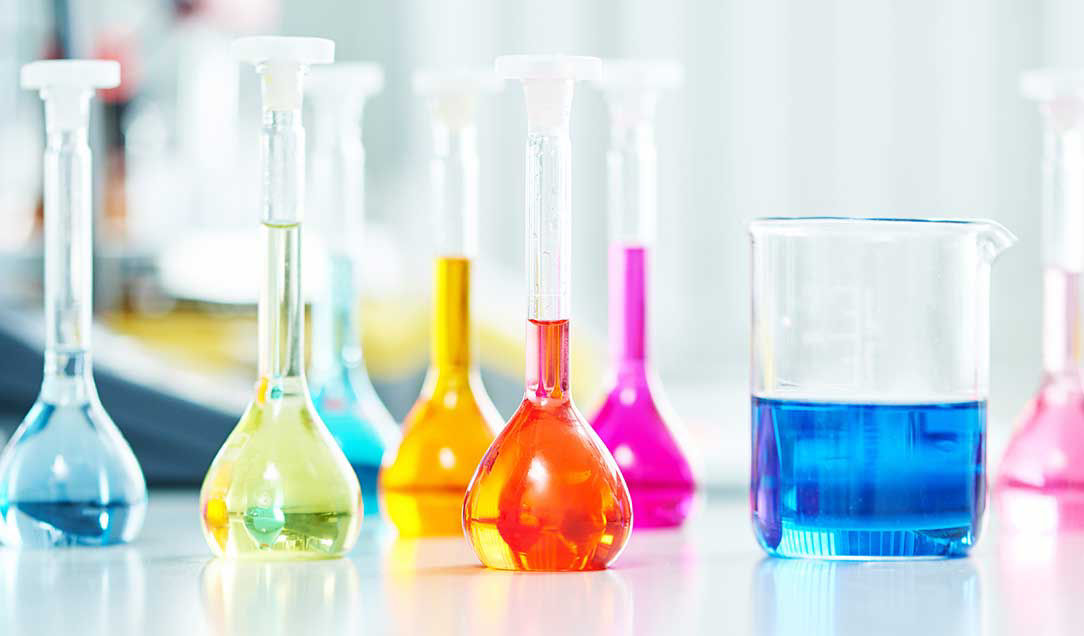 Flat-bottomed glass flasks filled with colored liquids.