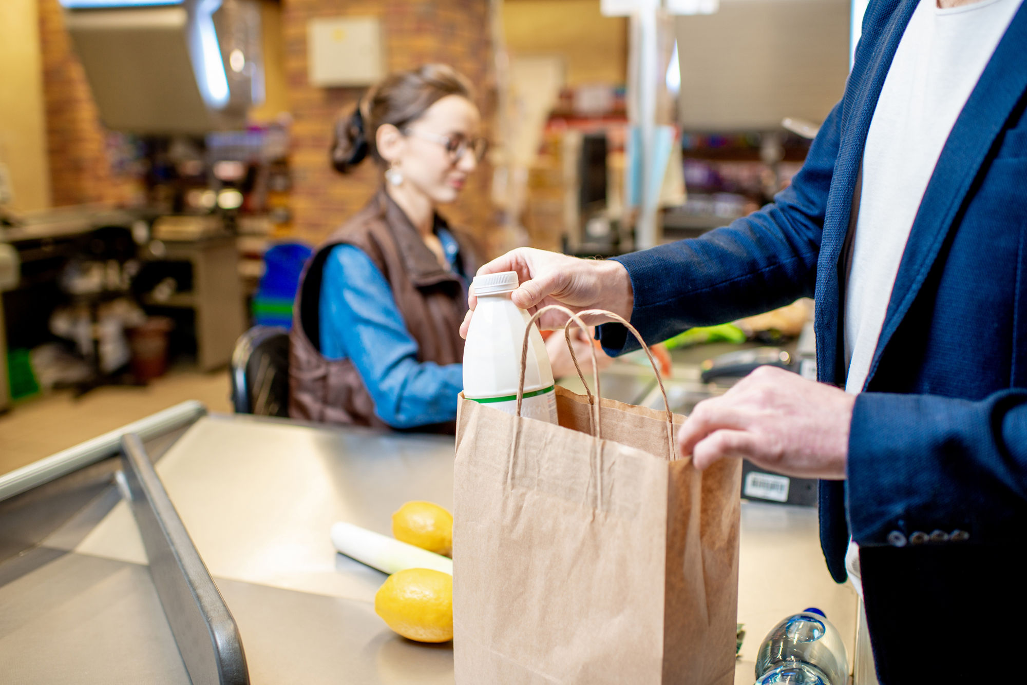 Businessman buying healthy food, packing products at the cash register with cashier on the background, close-up view