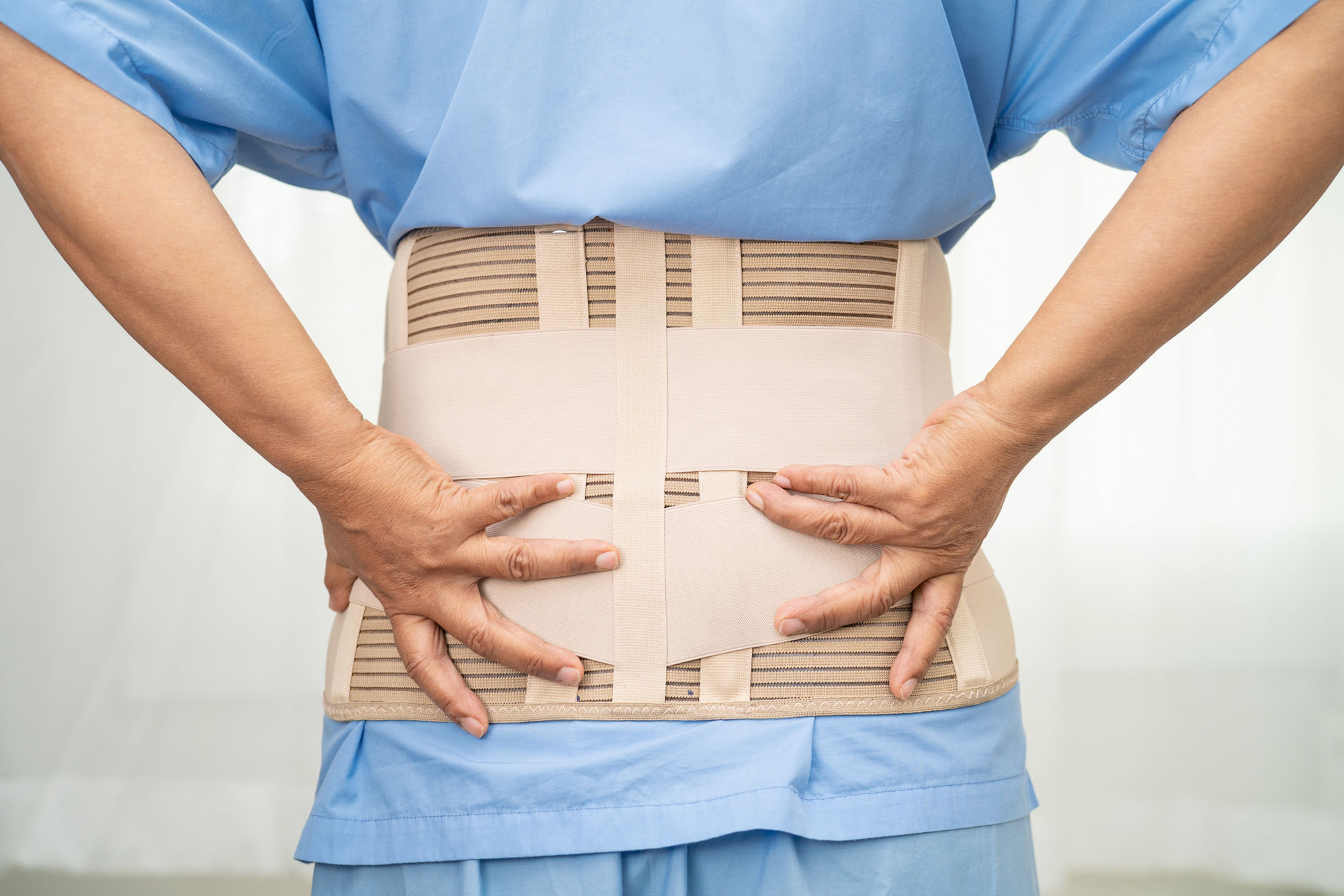 Asian lady patient wearing back pain support belt for orthopedic lumbar with walker.