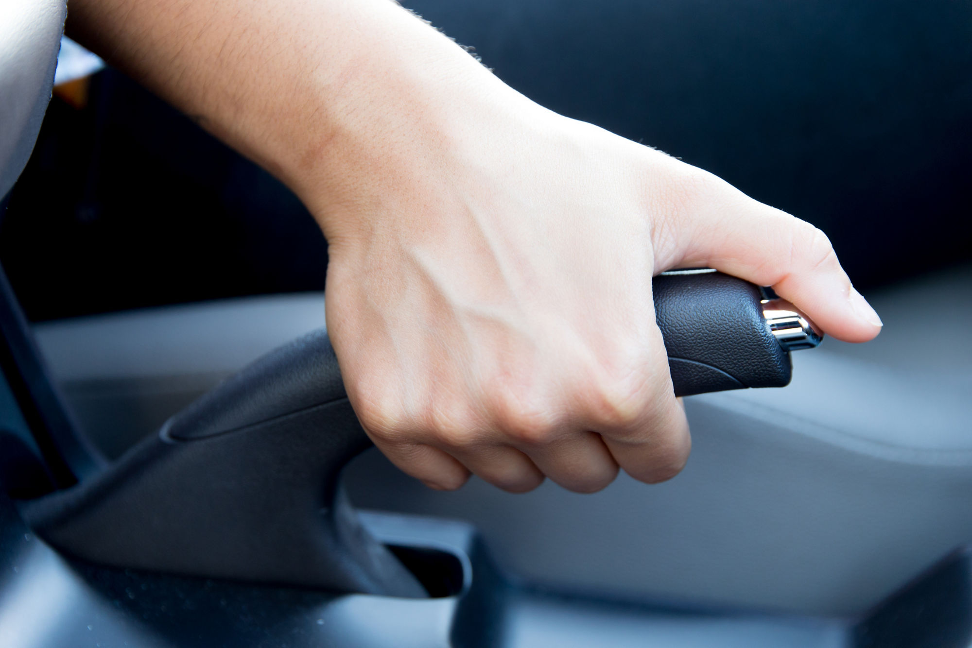 Eine Hand betätigt die Handbremse eines Autos.
