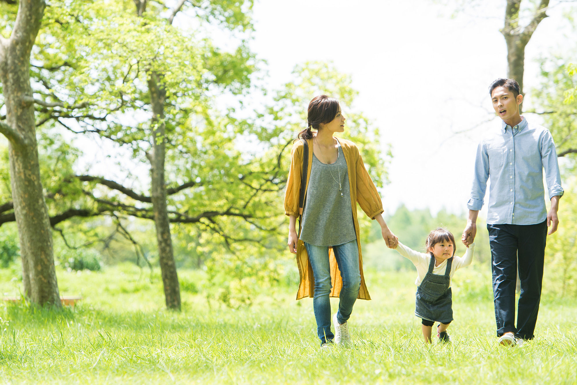 Photo Parents and their young daughter strolling in a lush park.