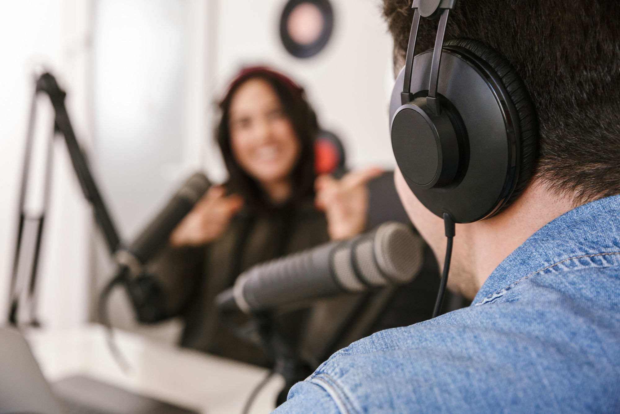 Man and woman in white shirts podcasters interview each other for radio podcast