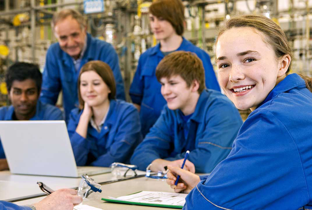 Several apprentices are sitting together in front of a laptop and discussing.