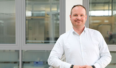 A man from the HR department leans against a railing in the company.