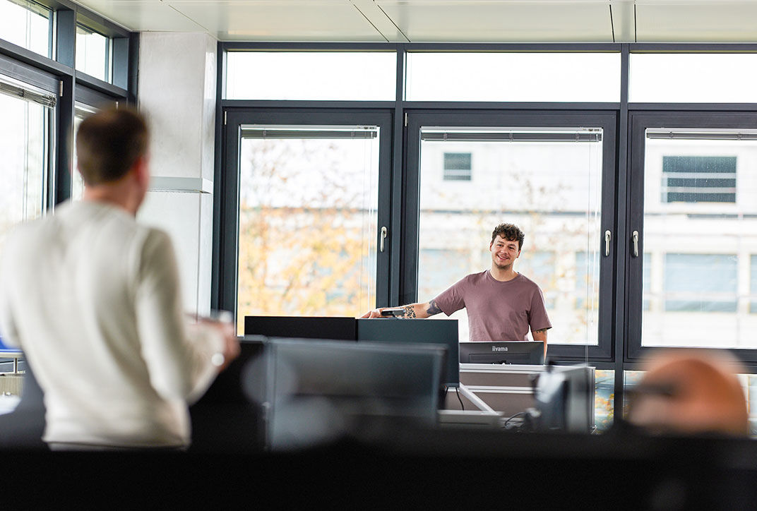 Two employees are standing in the office and talking.