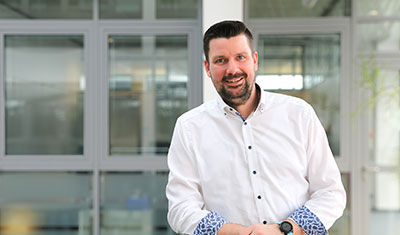 A man from the HR department leans against a railing and smiles in the company.
