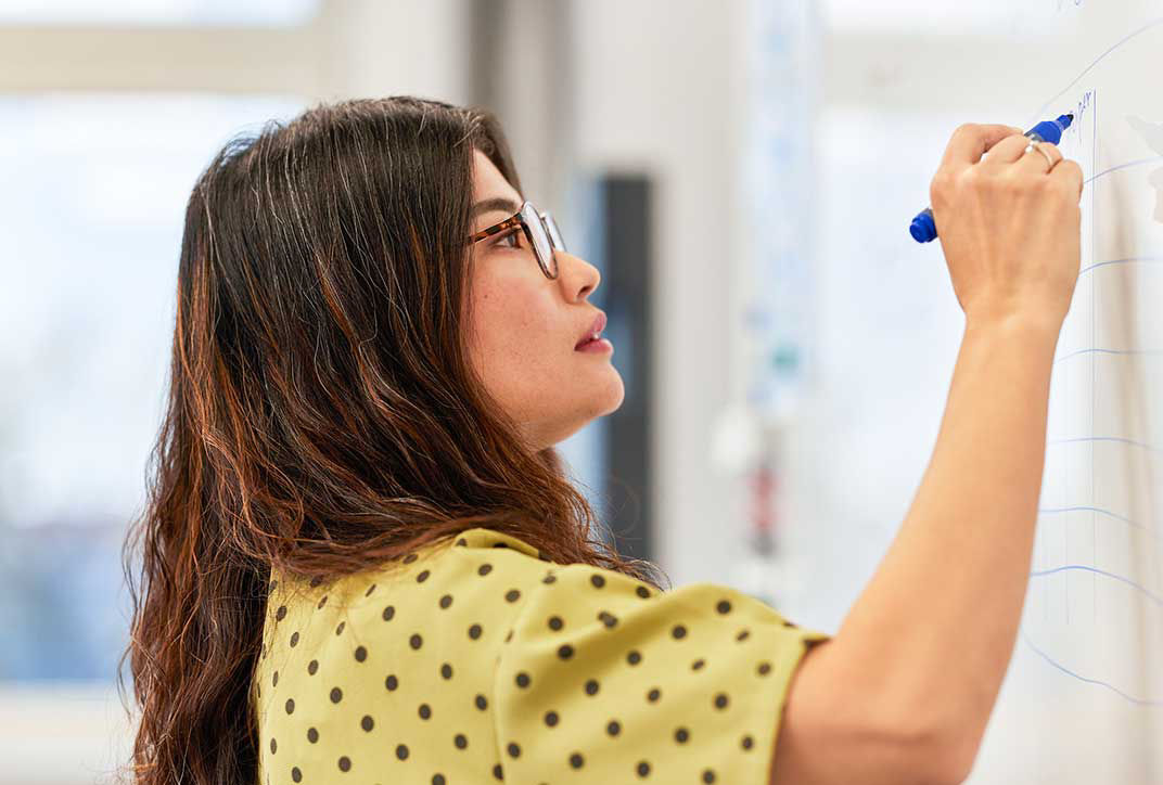 Eine Mitarbeiterin schreibt etwas auf ein Whiteboard.