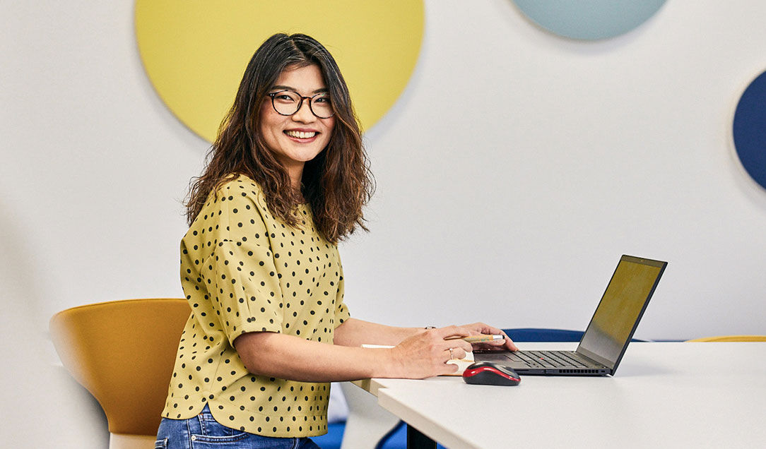 A female Kuraray employee stands with a laptop at a table.