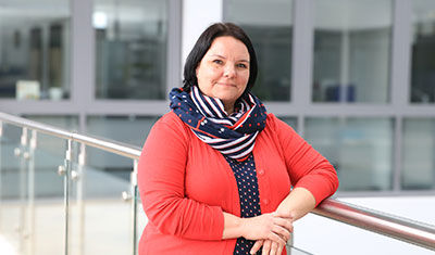 A woman from the HR department leans against a railing in the company.