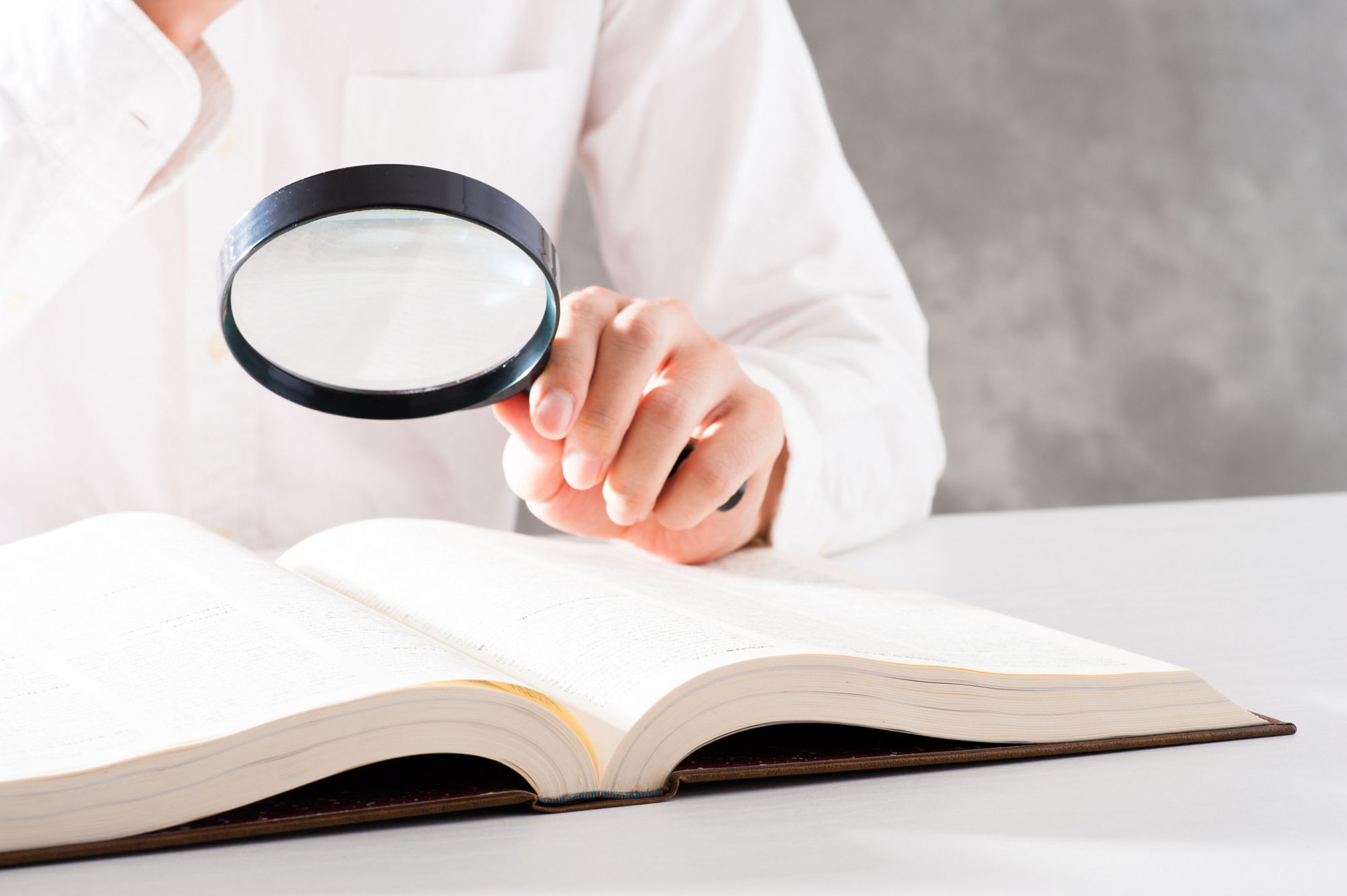 A person using a magnifying glass to look for information