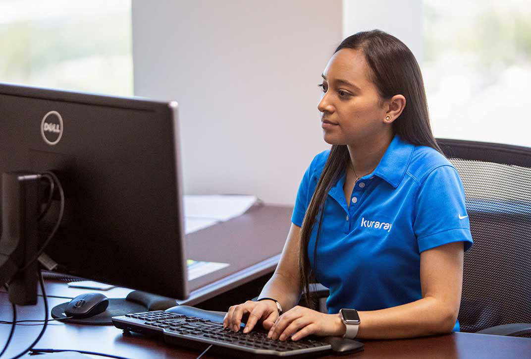 A female employee from Kuraray is sitting at a workstation.