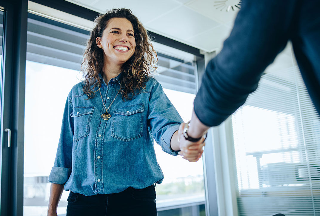 Two employees are greeting each other with a handshake.